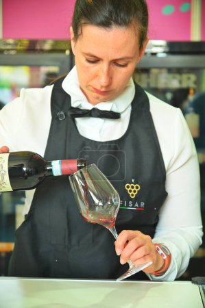 Photo for A closeup view of a female wine steward pouring red wine - Royalty Free Image