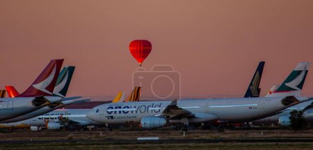 Foto de Un globo de aire caliente rojo sobre aviones estacionados en Alice Springs, Australia - Imagen libre de derechos
