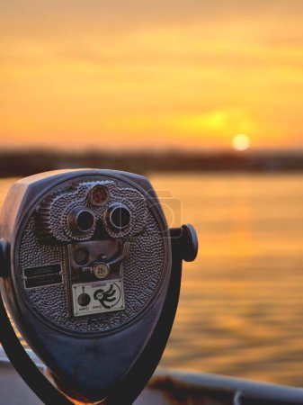Foto de Una toma vertical de un binocular operado con monedas con una hermosa puesta de sol dorada en el fondo. - Imagen libre de derechos