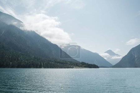 Téléchargez les photos : Une vue panoramique d'un océan bleu avec d'énormes montagnes en arrière-plan sous la lumière du soleil - en image libre de droit