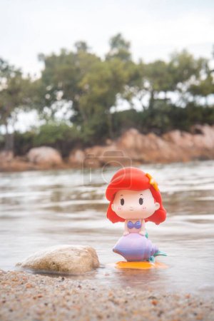 Foto de Una vista vertical de POP MART Disney princesa Ariel juguete en la arena de una playa - Imagen libre de derechos
