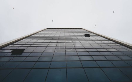 Téléchargez les photos : Un angle bas d'une tour avec façade en verre par un jour sombre - en image libre de droit