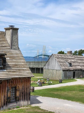 Photo for A vertical shot of a woman sitting by small buildings at Fort Michilimackina in Mackinaw, Michigan, USA - Royalty Free Image