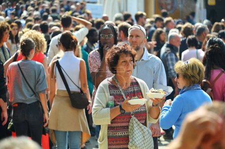 Téléchargez les photos : Une femme marchant dans une zone bondée tout en tenant de la nourriture de rue italienne dans ses mains - en image libre de droit