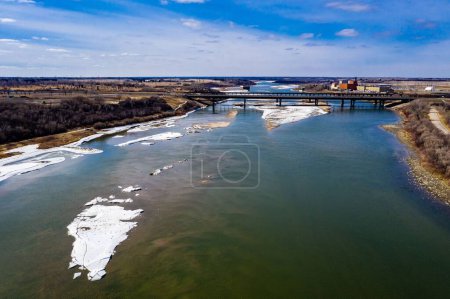 Téléchargez les photos : Un plan aérien de la rivière Saskatchewan Sud gelée et un pont au-dessus sous le ciel bleu - en image libre de droit