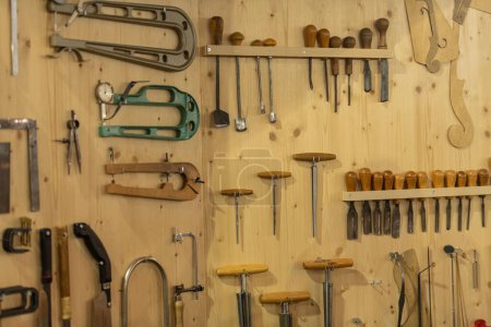 Photo for A set of different tools hanging on a wooden wall in a workshop - Royalty Free Image