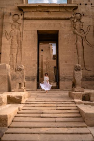 Téléchargez les photos : Plan vertical d'une femme en robe blanche debout à l'entrée du complexe du temple Philae. - en image libre de droit