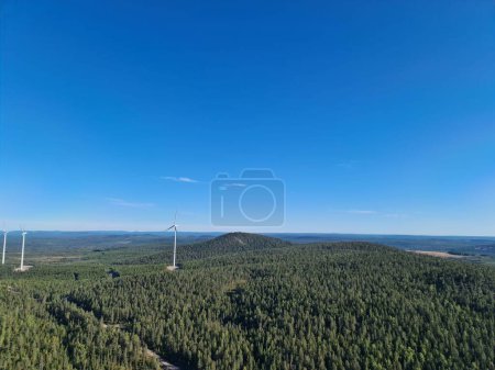 Téléchargez les photos : Une vue panoramique de la forêt de montagne avec de grandes éoliennes sous le ciel clair - en image libre de droit