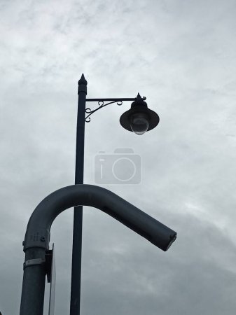 Foto de Un disparo vertical de una farola en la carretera a la luz del día en el fondo nublado del cielo - Imagen libre de derechos