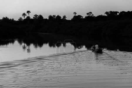 Foto de Fotografía en blanco y negro de un pescador remando su canoa en el río Jaguaripe, ciudad de Aratuipe, al final de la tarde. - Imagen libre de derechos