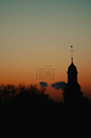 Foto de Una silueta de fondo vertical de una iglesia contra la escena naranja del atardecer - Imagen libre de derechos