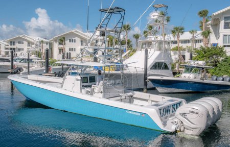 Téléchargez les photos : Un plan horizontal d'un bateau de pêche prétendant bleu à l'Ocean Reef Club avec des maisons de bord de mer blanches en arrière-plan - en image libre de droit