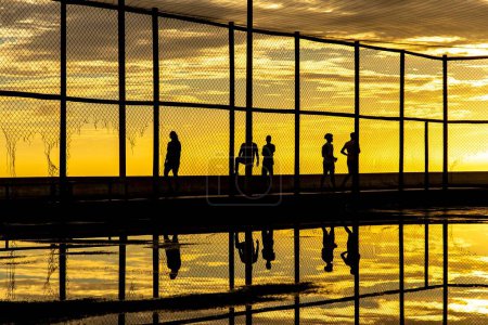 Téléchargez les photos : Silhouette de personnes au coucher du soleil s'exerçant sur le bord de la plage de Rio Vermelho dans la ville de Salvador, Bahia. - en image libre de droit