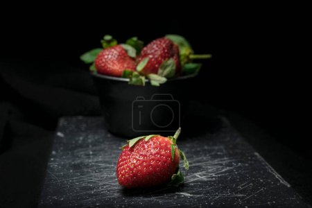 Photo for A closeup shot of fresh strawberries in a small black plate - Royalty Free Image