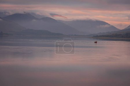 Téléchargez les photos : Un paysage océanique pittoresque contre les montagnes sous un ciel rose - en image libre de droit
