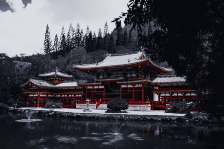 Téléchargez les photos : Un bas-angle d'un temple rouge et noir près du lac en hiver par une journée sombre - en image libre de droit