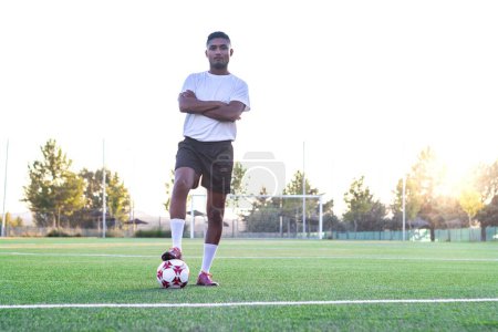 Téléchargez les photos : Un joueur de football sur le terrain avec son pied sur le ballon posant pour la caméra - en image libre de droit