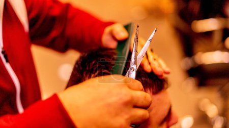 Foto de Un primer plano de un barbero caucásico cortando el pelo de su cliente. - Imagen libre de derechos