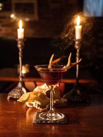 Photo for A vertical shot of a cocktail with lit candles in the background. - Royalty Free Image