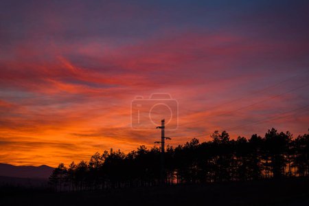Téléchargez les photos : Une vue spectaculaire sur le ciel au coucher du soleil, les lignes électriques et les stations silhouettes contre les nuages violets - en image libre de droit