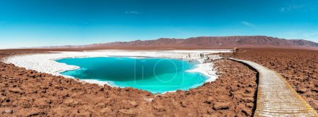 Photo for A panoramic view of tourists at an oasis with turquoise water lagoon in the Atacama desert, Chile - Royalty Free Image