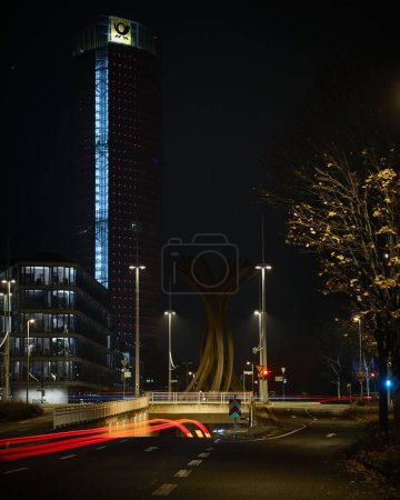Photo for A vertical long exposure shot of car light trails on a road near a downtown building in Bonn, Germany - Royalty Free Image