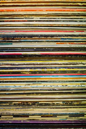 Foto de Una caja llena de discos de música de vinilo vintage con cubiertas coloridas que crean un patrón de línea - Imagen libre de derechos