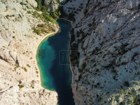 Photo for An aerial top view of the rocky coast of Zavratnica Bay and the waters of the Adriatic sea in between - Royalty Free Image