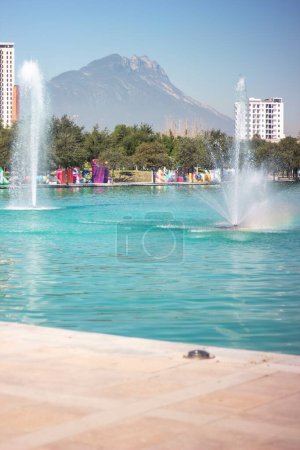 Téléchargez les photos : Vue verticale des fontaines dans le parc public sur fond de montagne - en image libre de droit