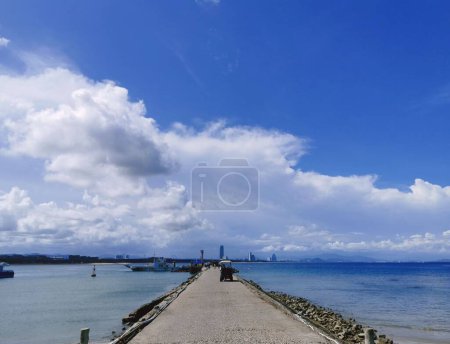 Foto de Un paseo marítimo de piedra que conduce al mar en un día soleado, cielo nublado en el fondo - Imagen libre de derechos
