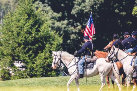Foto de Un soldado montando un caballo y levanta la bandera de Estados Unidos durante el desempeño militar en la recreación de la guerra civil en la ciudad de Jackson, Michigan, EE.UU. - Imagen libre de derechos