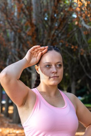 Photo for A closeup shot of a tired sporty girl with her hand on her forehead in a park - Royalty Free Image