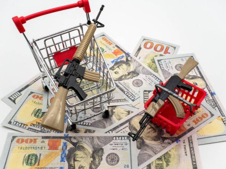 Photo for A high angle shot of USD cash with plastic gun toys and trolleys on it - Royalty Free Image