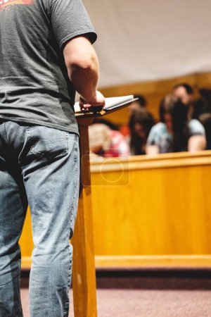 Photo for Male preaching to praying people while holding onto a pulpit - Royalty Free Image