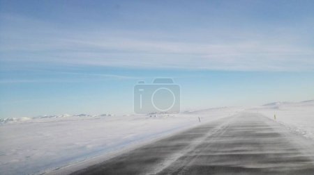 Téléchargez les photos : Une route et des champs couverts de neige et de brouillard sous le ciel bleu par une froide journée d'hiver - en image libre de droit