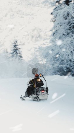 Foto de Un turista montando una moto de nieve en un campo cubierto de nieve durante el invierno - Imagen libre de derechos