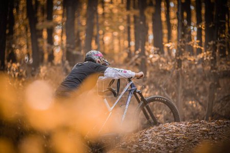 Téléchargez les photos : Un tir d'un cavalier portant holeshotpunx sweat à capuche tout en faisant des tours de vélo dans une forêt - en image libre de droit