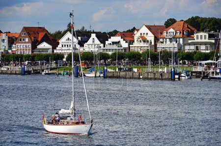 Téléchargez les photos : Un bateau naviguant sur la rivière Trave entouré de bâtiments traditionnels lors d'une journée d'été en Allemagne - en image libre de droit