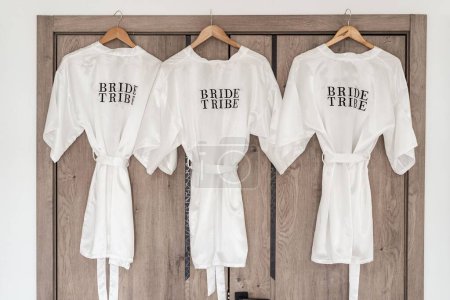 Photo for A closeup of three white Bride tribe robes on hangers - Royalty Free Image
