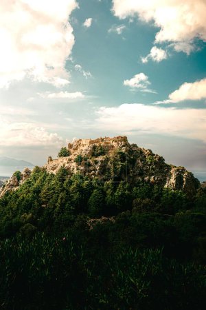Téléchargez les photos : Un plan vertical d'une colline rocheuse couverte de vert sous le ciel nuageux bleu, frais pour l'arrière-plan - en image libre de droit