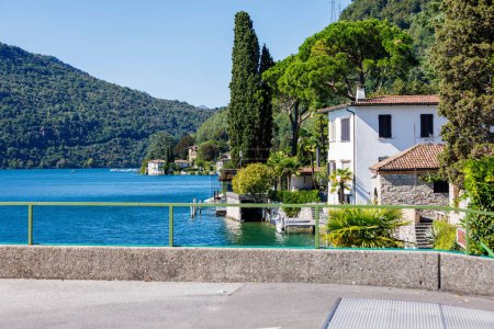 Téléchargez les photos : Une vue panoramique de maisons blanches sur un rivage d'un lac bleu dans les montagnes verdoyantes par une journée ensoleillée - en image libre de droit
