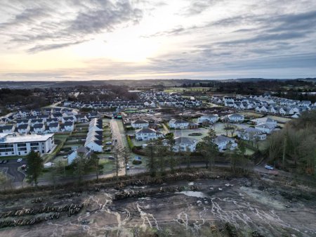 Foto de Un disparo de dron de edificios residenciales y casas en una ciudad cerca de un campo con árboles cortados - Imagen libre de derechos