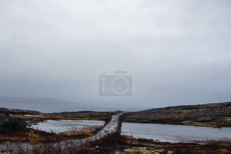 Téléchargez les photos : Un paysage de collines de canyon au bord du lac avec un ciel nuageux brumeux à l'horizon - en image libre de droit