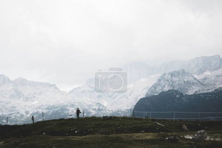 Photo for A scenic landscape of snow covered mountains with a person mowing the grass on a winter day - Royalty Free Image