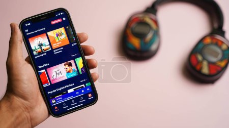 Téléchargez les photos : Application musicale Gaana sur smartphone, téléphone intelligent ios, écran iPhone 12, isolé sur fond couleur - en image libre de droit
