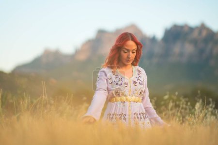 Téléchargez les photos : Une belle dame aux cheveux roux avec une robe blanche brodée et une ceinture dorée dans un champ ensoleillé en Espagne - en image libre de droit