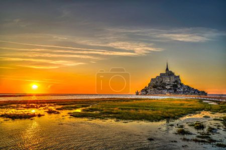Téléchargez les photos : Une vue panoramique sur l'île du Mont Saint-Michel avec un beau coucher de soleil visible en arrière-plan - en image libre de droit