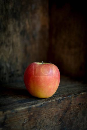 Photo for A vertical shot of an apple with an old wooden background - Royalty Free Image