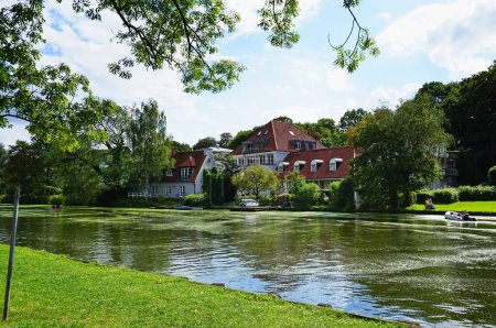Téléchargez les photos : Une vue panoramique sur la paisible rivière Trave entourée de bâtiments traditionnels et de verdure en Allemagne - en image libre de droit