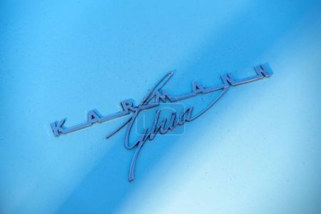 Téléchargez les photos : Un emblème arrière de Volkswagen Karmann Ghia coupé classique. Une photo en gros plan du logo chromé sur le corps peint en bleu bébé. - en image libre de droit